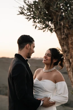 Ayoub & Chaimae goldenhour photoshoot. witte parelketting, klassiek zwart pak, moderne off shoulder bruidsjurk