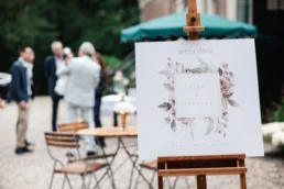 Linh & Timothy's oudroze klassieke welkomstbord met gasten op de achtergrond